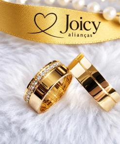 Alianças de casamento ouro 18K Elegance apoiadas, com fita dourada Joicy Alianças e pérolas ao fundo