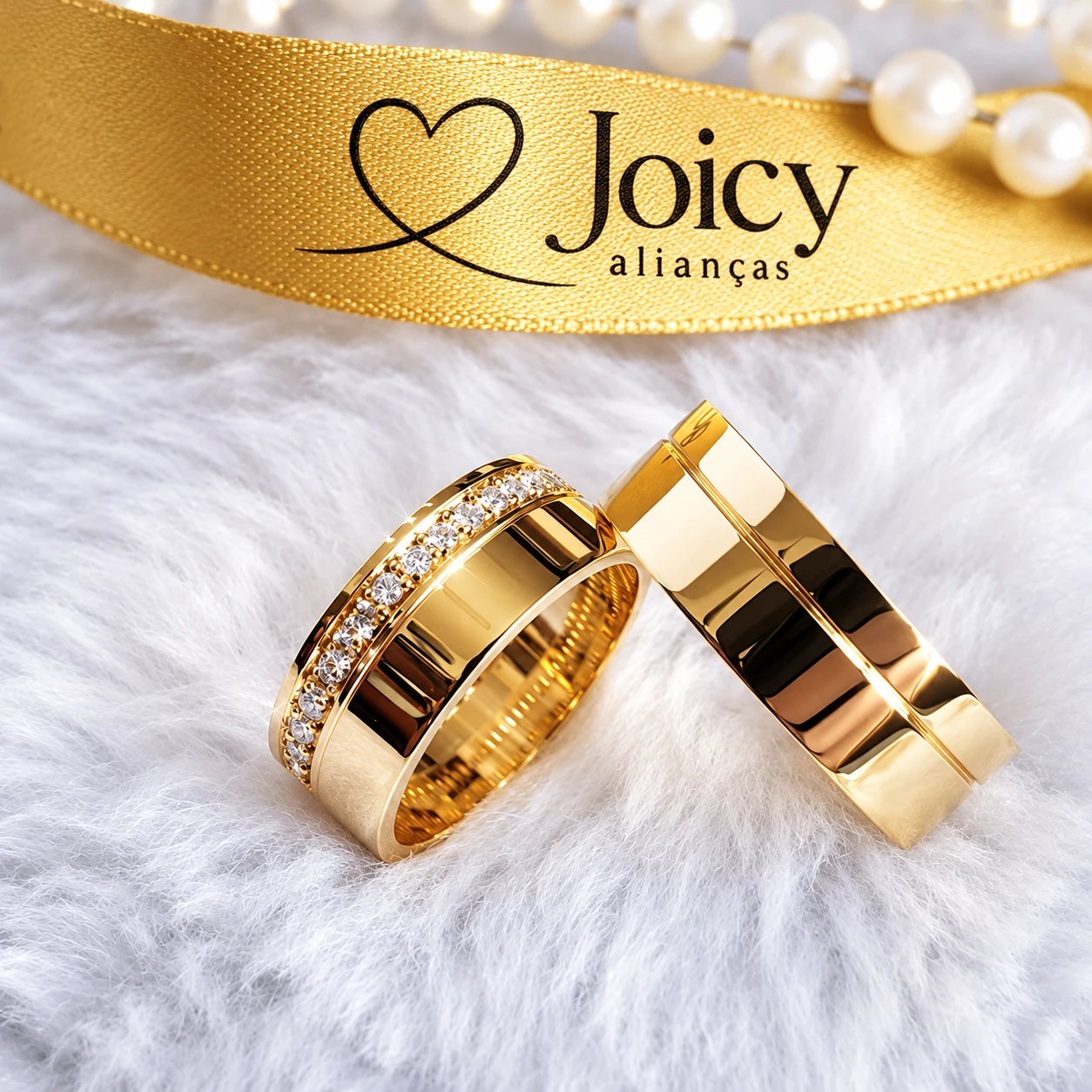 Alianças de casamento ouro 18K Elegance apoiadas, com fita dourada Joicy Alianças e pérolas ao fundo
