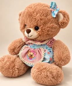 Ursinha de pelúcia de 30cm de lado, mostrando o laço azul estampado, o vestido floral e o avental rosa com bordado