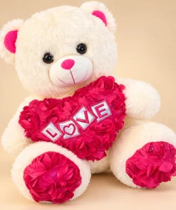Urso de pelúcia creme de 30cm sentado, abraçando coração rosa com flores 3D e LOVE bordado